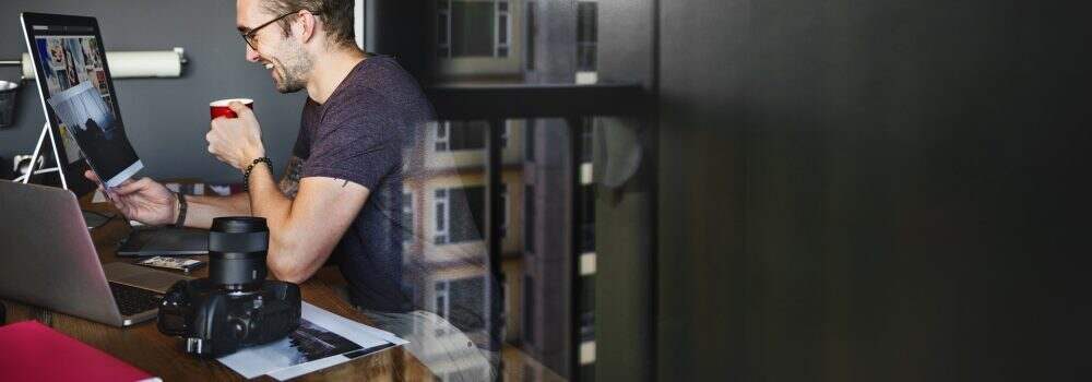 A Man is Leisurely Enjoying a Cup Of Coffee While Working On His Desktop